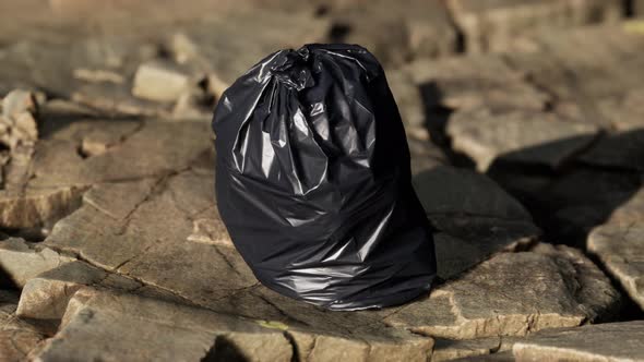 Black Trash Bag Lay on a Rocky Beach