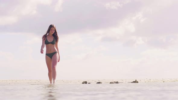 Brunette Woman in Swimsuit Walking on Sea Water at Tropical Beach. Attractive Woman in Bikini