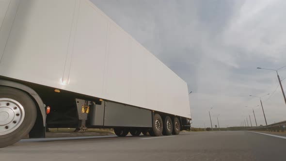 Truck with white trailer is driving on road