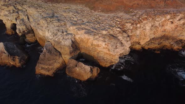 Drone top down aerial view of waves splash against rocky seashore, background. Flight over high clif