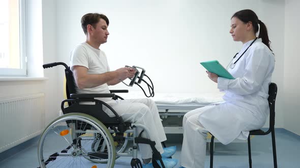 Side View Concentrated Rehabilitologist Talking to Patient Exercising with Resistance Band Sitting