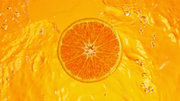 Super Slow Motion Shot of Orange Slice on Orange Gradient Background and Rippling Water at 1000 Fps.
