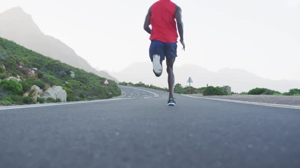 Fit african american man exercising running on a country road near mountains