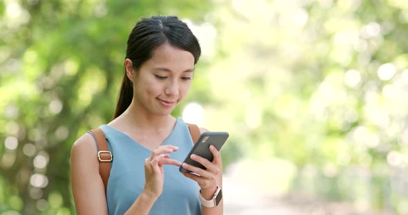 Woman use of mobile phone with the background of countryside 