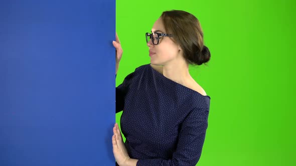 Business Woman Looks Out From Behind a Blue Board and Shows a Thumbs Up. Green Screen