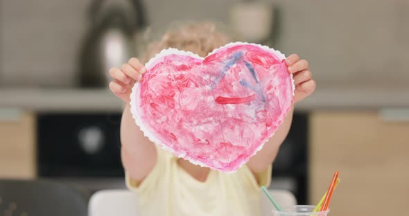 Close Up of a a Red Heart Cutted and Drawed By the Little Girl with Watercolors Presenting It to