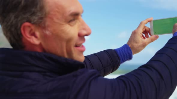 Mature man taking picture of view from mobile phone