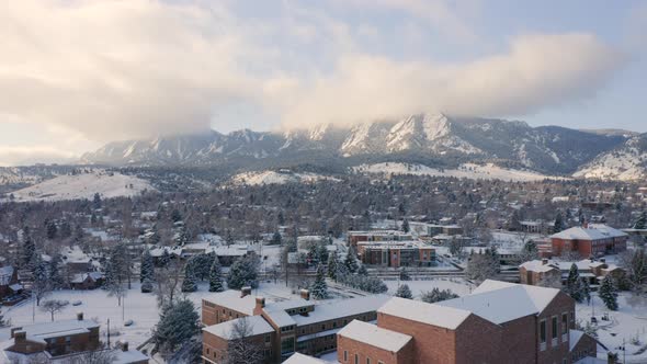 Aerial drone moving backward over University of Colorado Boulder campus covered in snow on a winter