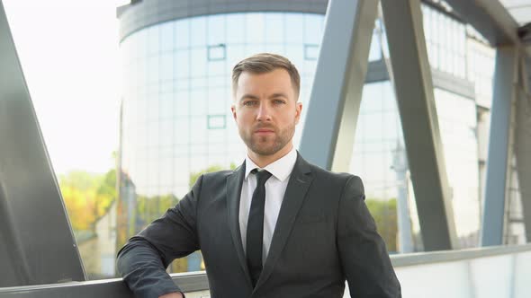 A Handsome Businessman Looking Into the Camera Outside Modern Commercial Complex