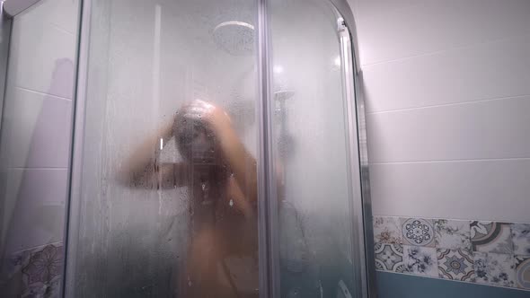 Man taking shower washes his hair underwater in shower in shower.