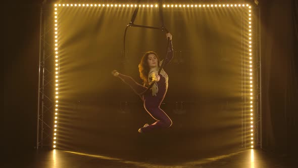 Aerial Acrobat in the Ring. A Young Woman Performs the Acrobatic Elements in the Air Ring Surrounded