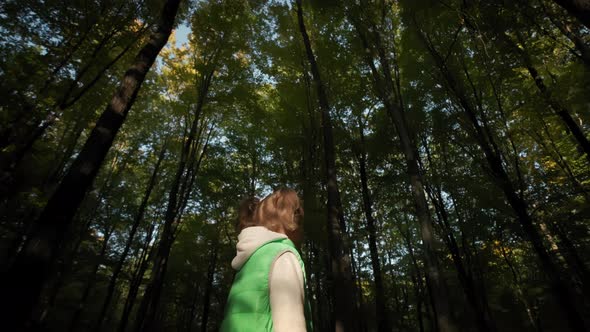 Little Girl Walking Through Tall Trees in Forest