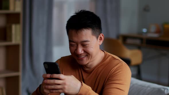 Happy Middle Aged Asian Man Texting on Smartphone on Web Surfing in Social Media Tracking Shot Slow