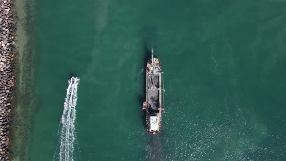 Unique view of a fasting personal watercraft passing a large industrial sand dredging ship next to a