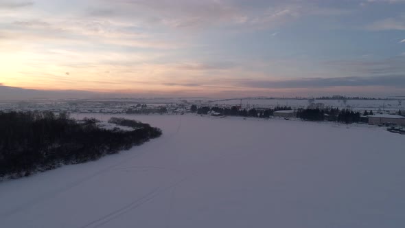 Aerial Over the Frozen Snow Covered Winding River Surrounded with a Little Village on a Side Siberia