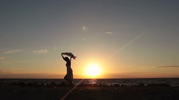 Woman Running with Flying Scarf on Beach at Sunset