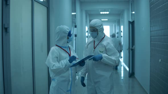 Man and Woman in Hazmats Work Together in Hospital.