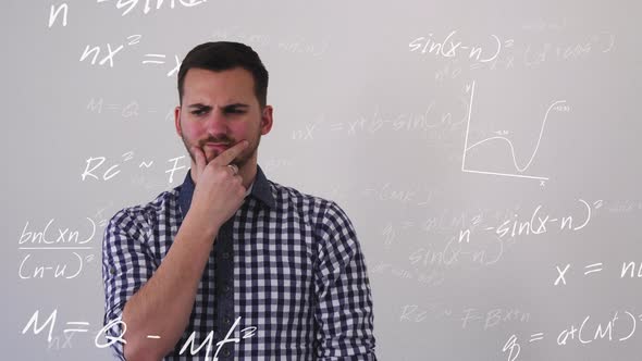 Young man in front of white background surrounded by mathematical formulas and diagrams thinks about