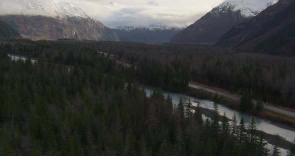 Aerial footage across snowy Alaskan mountaintops and clouds, drone helicopter footage