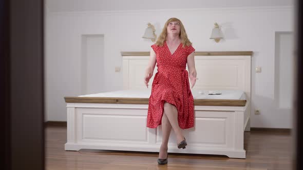 Stressed Troubled Caucasian Transgender Woman Closing Ears with Hands Sitting on Bed Freaking Out