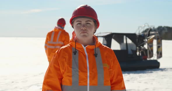 Portrait Professional Female Lifeguard Posing at Camera While Colleagues Loading Gear in Hovercraft