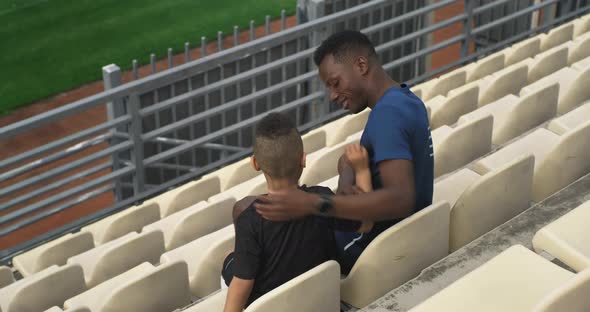 Diverse Father and Son Hugging and Watching Match on Stadium
