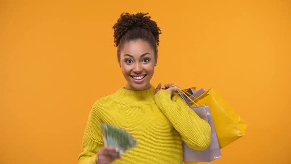 Cheerful Black Lady Holding Bunch of Euros and Shopping Bags, Holiday Sale