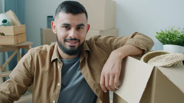 Slow Motion Portrait of Goodlooking Middle Eastern Guy Sitting in New House with Boxes