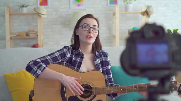 Portrait Young Woman Blogger Sitting on the Couch with a Guitar in His Hands in Front of the Camera