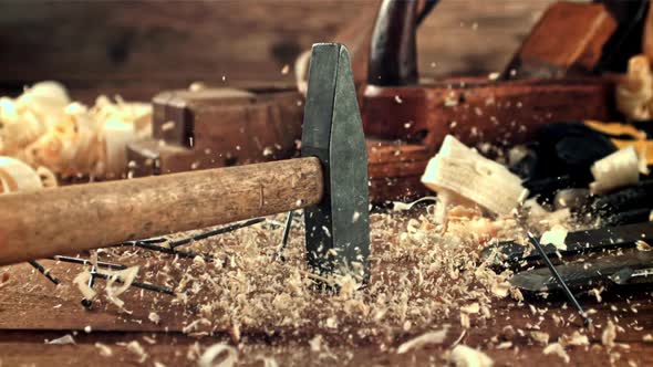 A Hammer Falls on a Table with Sawdust and Nails