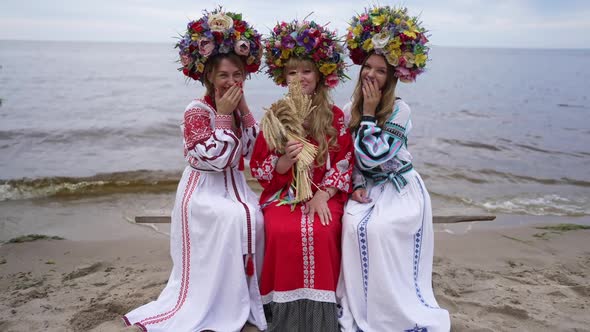 Laughing Young Beautiful Ukrainian Daughters Sitting with Mother on Bench on River Bank Talking