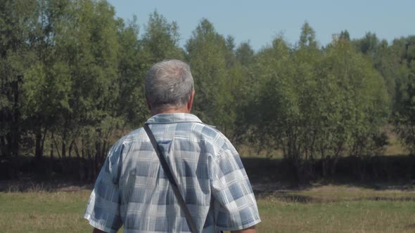 Active Pensioner in Jeans Walks Along Green Lawn Actively