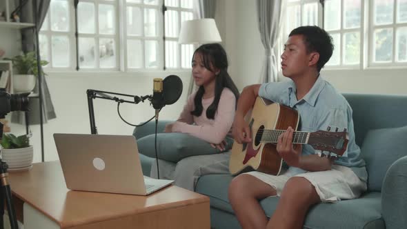 Boy Playing Guitar And Girl Sing A Song While Streaming. The Children Is Broadcasting Live