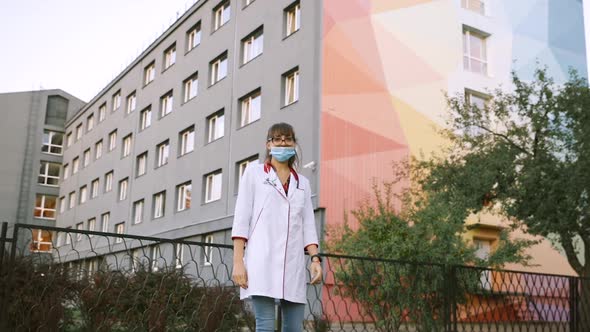 Happy Beautiful Young Doctor Takes Off Surgical Face Mask and Wears LGBT Bracelet