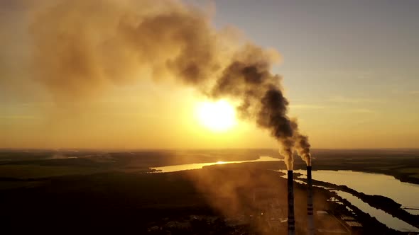 Industrial pipes with thick smoke at sunset. Two large pipes produce chemical smoke