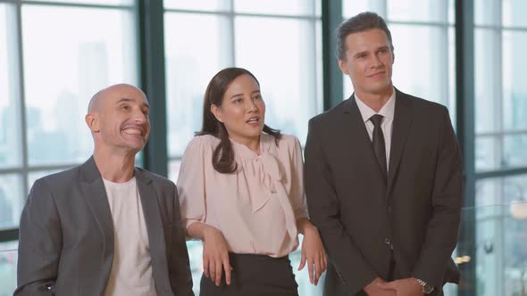 Three business people, male and female business people discussing work standing in office building 