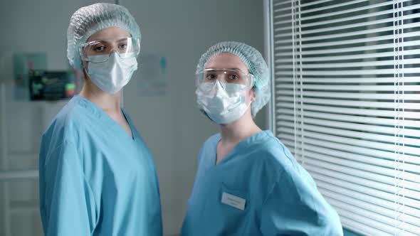 Two Female Nurses in Protective Uniforms Posing for Camera in Clinic