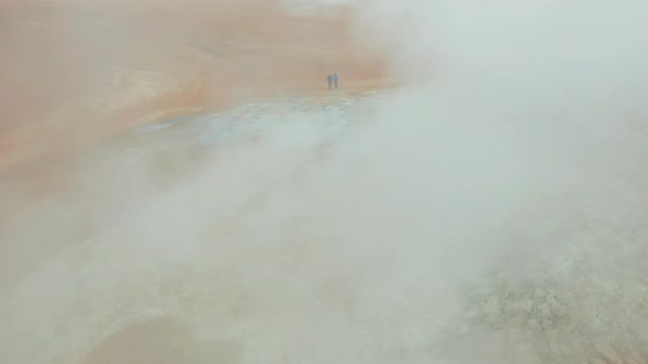 Two Tourists in Front of Steaming Fumaroles in Hverir Geothermal Area