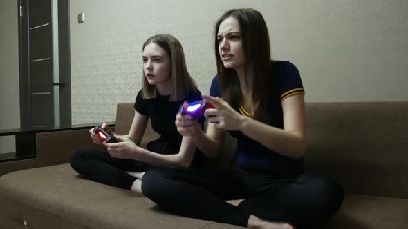 Two Sisters Play Games on the Joysticks at Home, Leisure