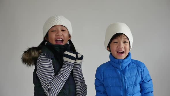 Cute Asian Children In Winter Clothes Is Surprise And So Happy About It On Gray Background