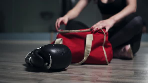 Unrecognizable Woman Sitting on the Floor and Taking From Her Bag Gloves for Boxing Preparing for