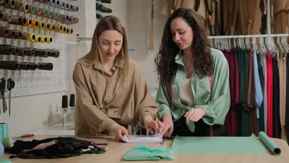 Two young adult fashion business female merchant sellers in the studio workshop working 