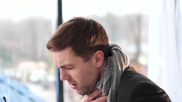 Sick Young Man Sitting on the Sofa Wrapped in Blanket