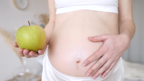 Pregnant Girl Holding A Green Apple Near Her Belly