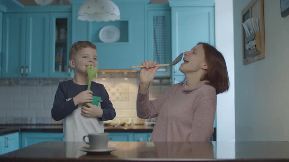 Happy family dancing and singing into kitchenware like a microphone