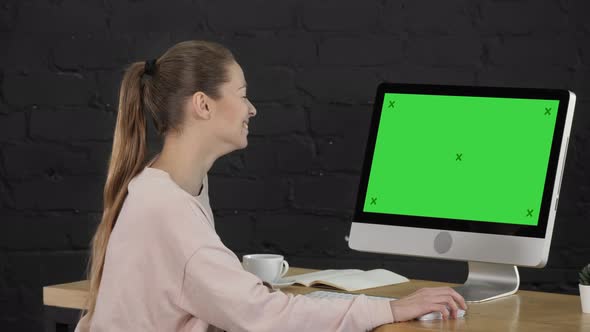 Young Woman with Blond Hair Working on Computer and Laughing. Green Screen Mock-up Display