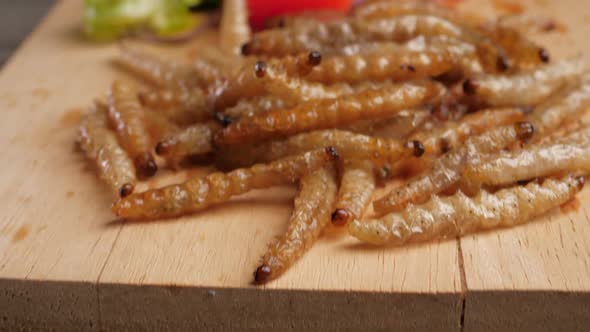 Fried Bamboo Caterpillar on the wooden plate. Insects are foods that are high in protein.