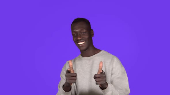 Young African American Man Smiling and Dancing in Good Mood on Blue Background