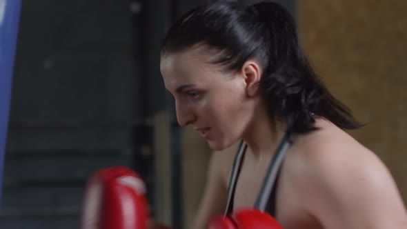 Female Boxer Punching Heavy Bag in Gym