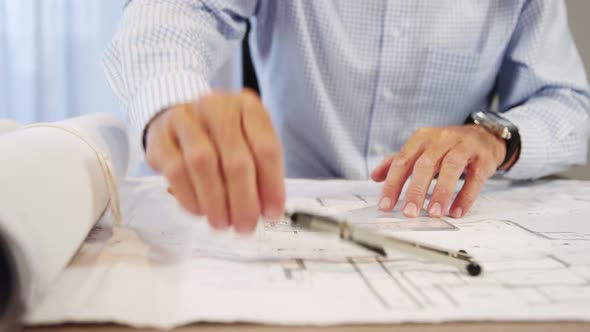 Mid-section of architect working on blueprint